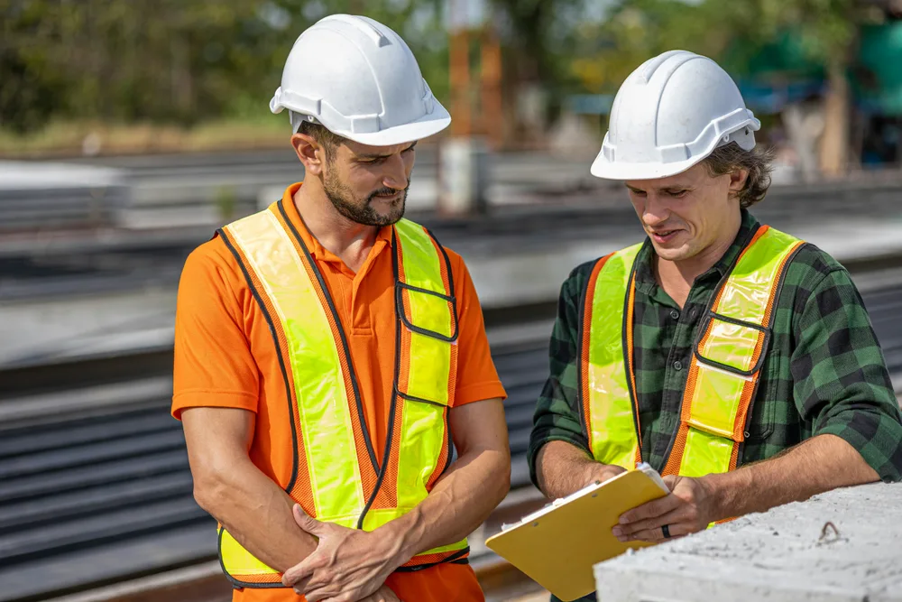 Two workers reviewing documents on a construction site